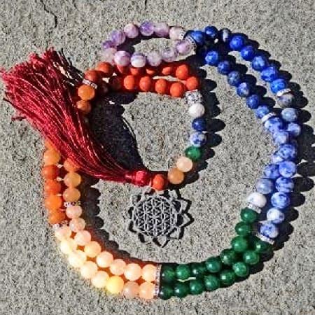 Chakra Rainbow Mala Prayer Beads – 108 Gemstone Japa Mala, colorful gemstone prayer beads with a decorative pendant and red tassel, arranged on a gray surface.