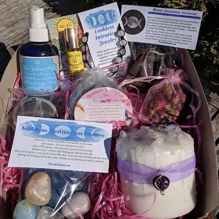 Goddess Gift Set, a collection of spiritual and wellness products including a blue spray bottle, moon goddess incense, gemstone heart, candle with purple ribbon, and various affirmation cards.